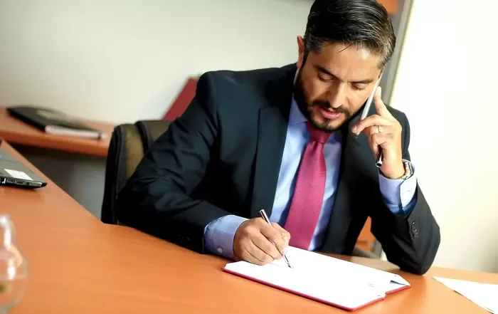 lawyer taking notes while on talking on phone