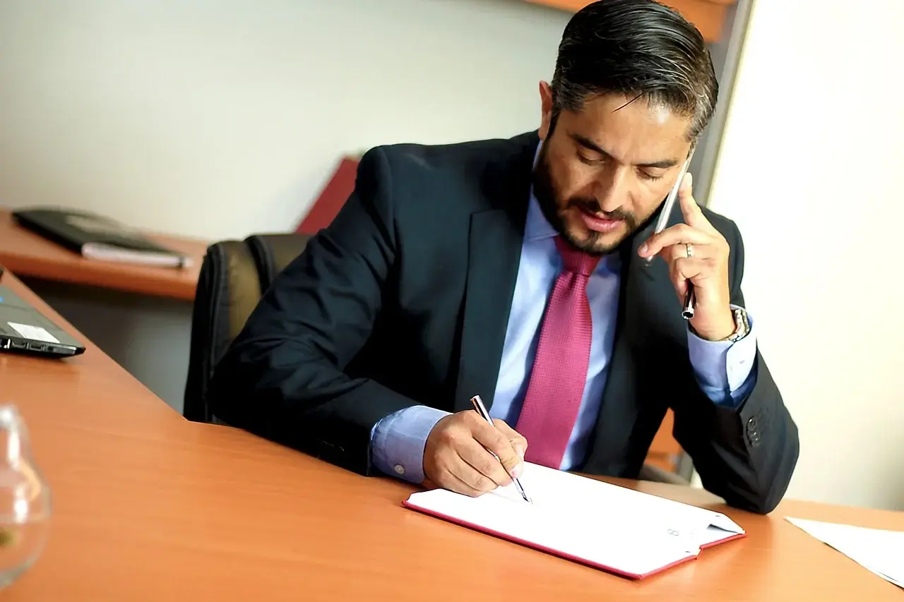 lawyer taking notes while on talking on phone