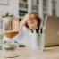 hourglass in foreground, out-of-focus woman with hand on head in background